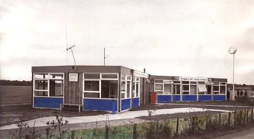 Another hand tinted view of the Gregory School of Flying, showing the Air Taxi offices on the other end of the building.